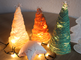 gebastelter Weihnachtsbäume aus Wollresten mit Lichterketten dekoriert.