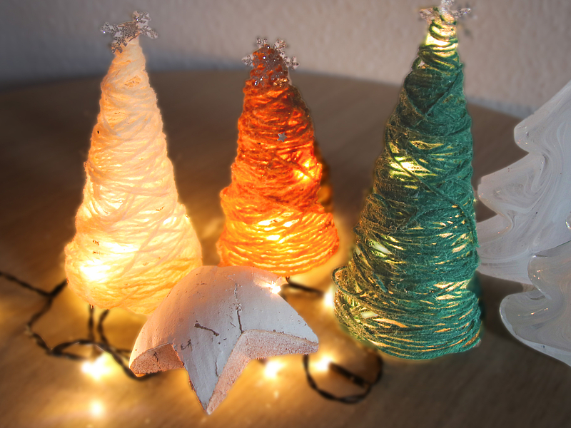 gebastelter Weihnachtsbäume aus Wollresten mit Lichterketten dekoriert.