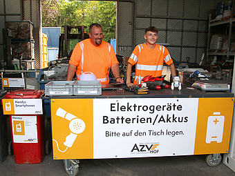 An der Theke für Annahme von Elektrogeräten am Wertstoffhof Hof stehen zwei Mitarbeiter