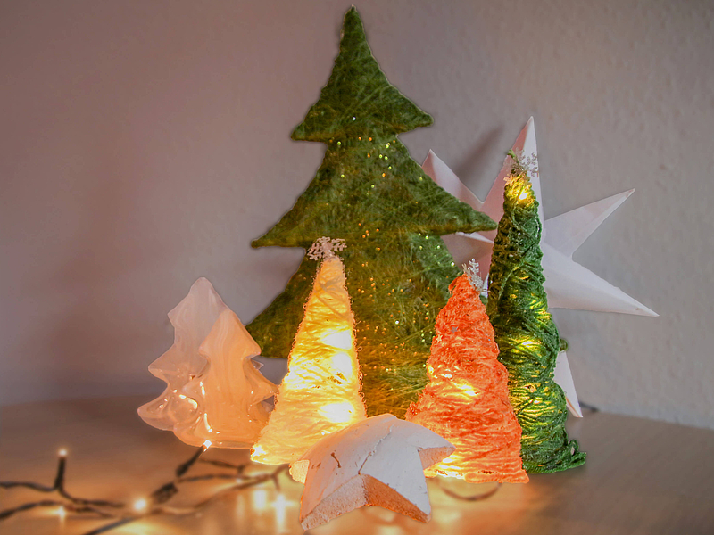 gebastelter Weihnachtsbäume aus Wollresten mit Lichterketten dekoriert.