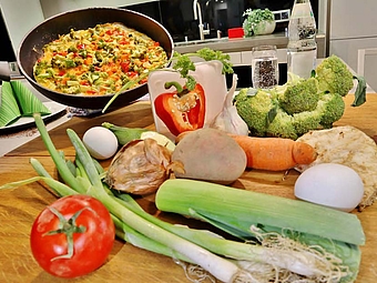 Verschiedenes Gemüse liegt auf einer Arbeitsplatte in einer Küche.