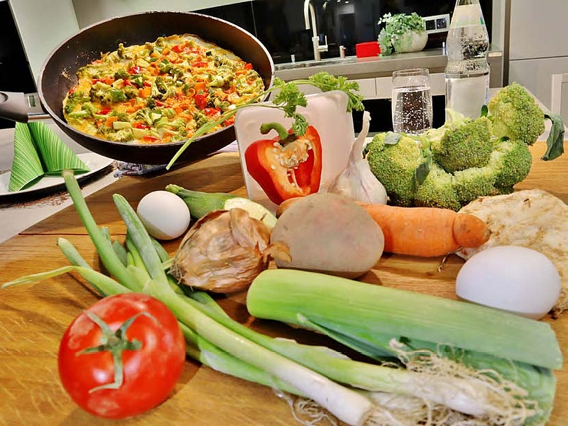 Verschiedenes Gemüse liegt auf einer Arbeitsplatte in einer Küche.